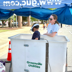 GUC employee and child playing a virtual reality bucket truck game