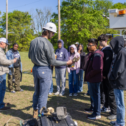 Mike McGowan and Jordan Lang help Wellcome Middle School students try on lineworker gear 