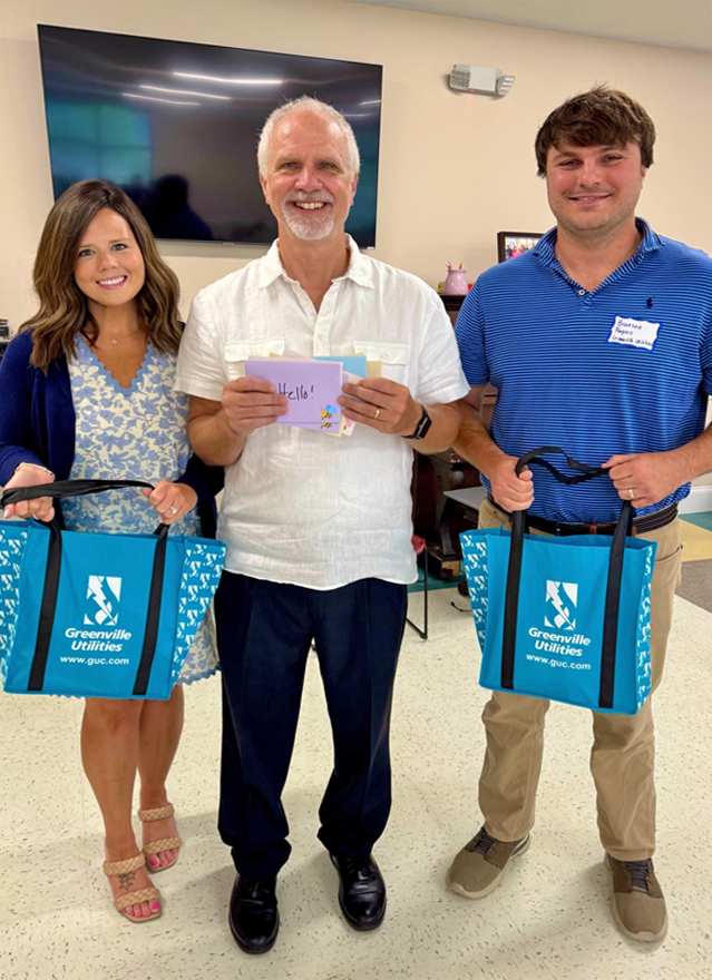 Jessica Hardy, Branson Rogers, and Rich Zeck pose for a photo with GUC bags