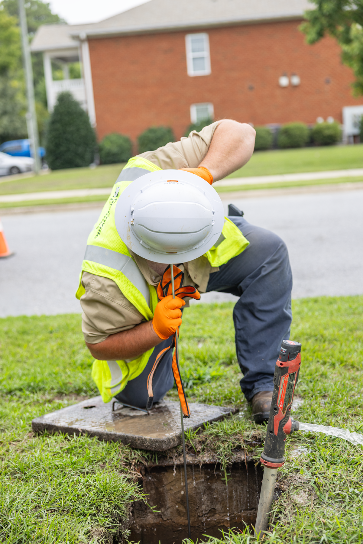 Dylan uses the listening stick to identify on what side of the meter the water leak is coming from.