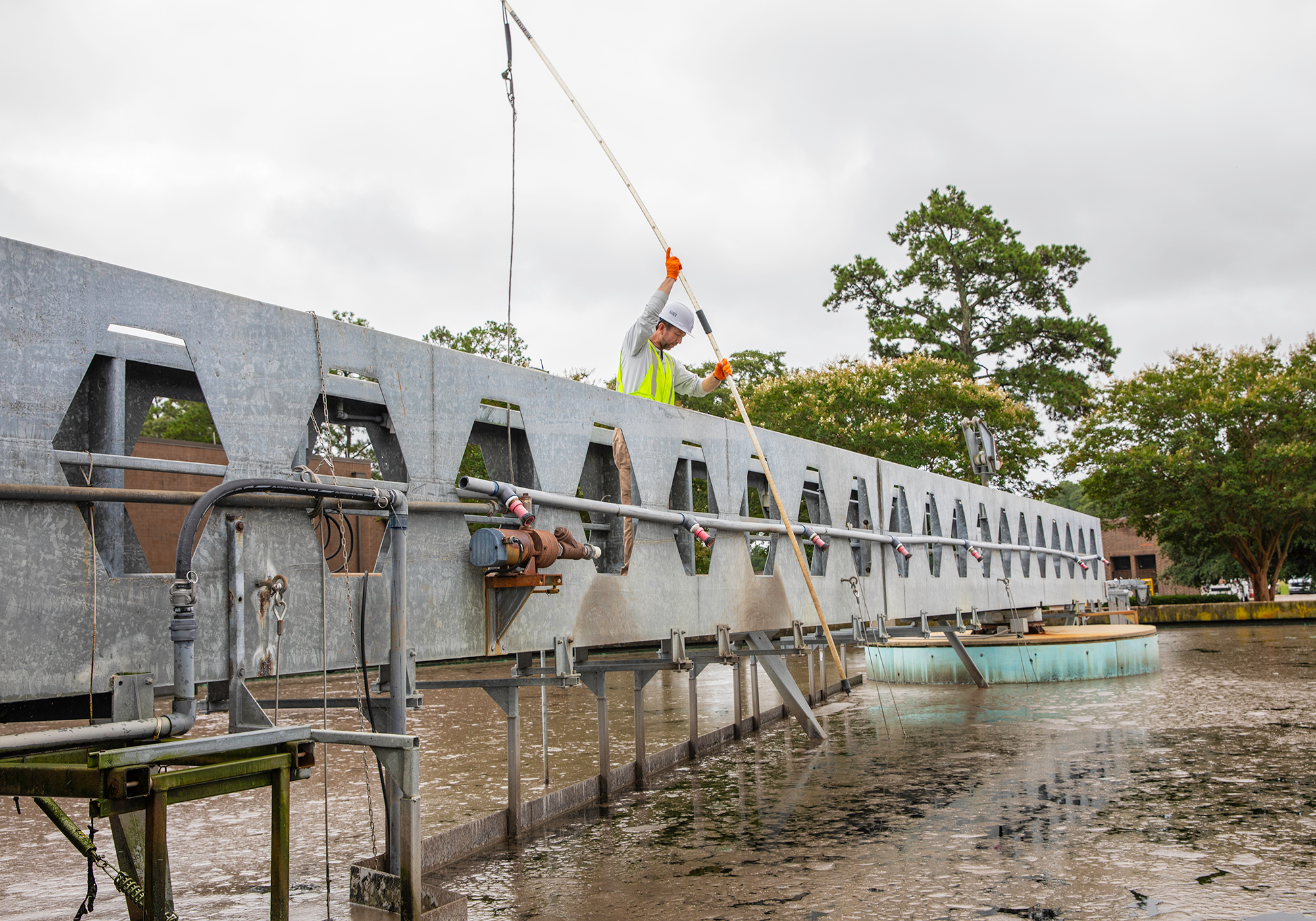 Operator II Jason Harmon checks the sludge depth in clarifier three with a sludge judge.